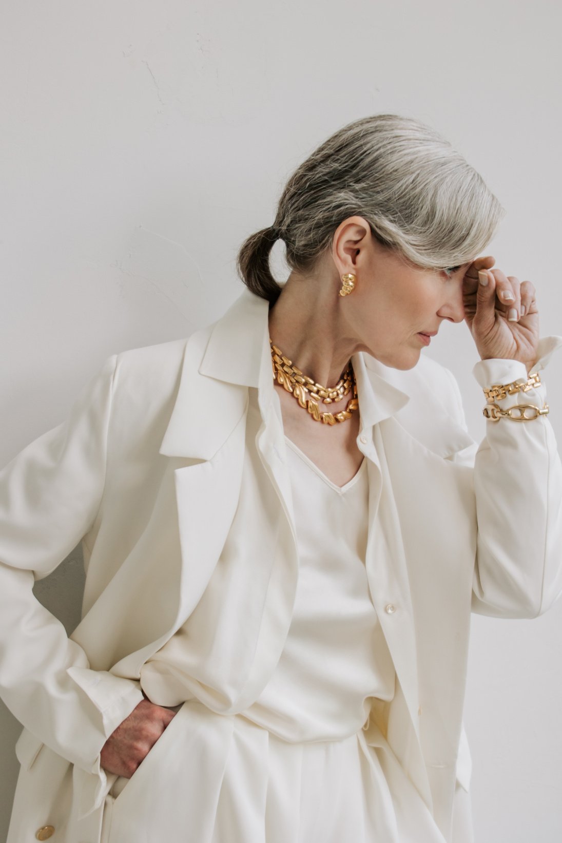 Senior Woman in White Outfit and Gold Accessories